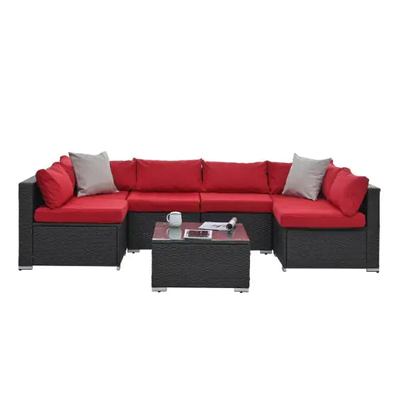 Black PE rattan patio furniture sectional with red cushions and glass coffee table