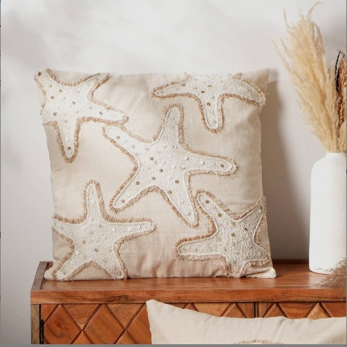 Neutral beige pillow case with textured starfish embroidery on wooden surface by Shopi Vella