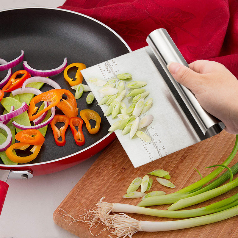 Shopi Vella pizza dough cutter tool scraping chopped green onions into a red frying pan