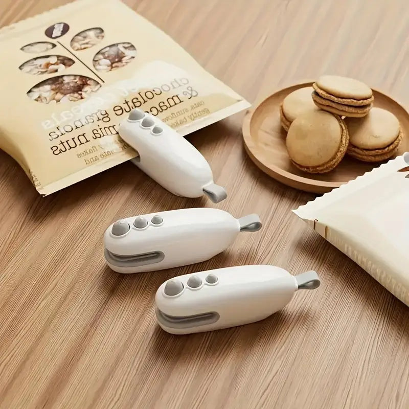 Shopi Vella portable chip bag resealer with cutter in white on wooden table with snacks