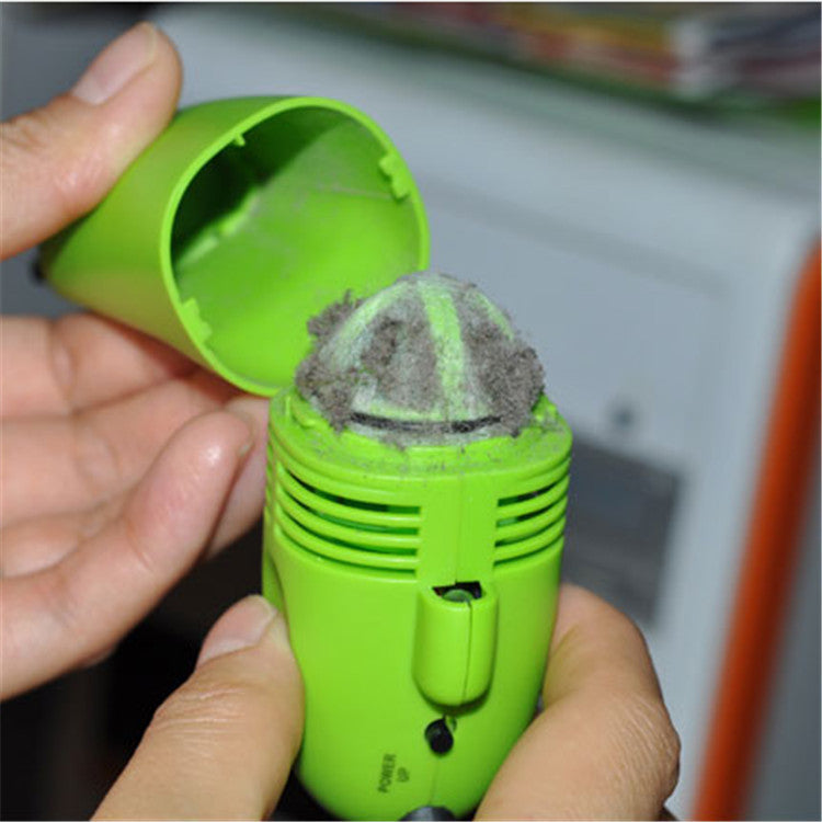 Green portable computer keyboard brush with dust captured on bristles held in hands