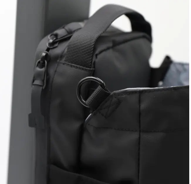 Close-up of black portable magnetic water bottle pouch attached to a black bag with sturdy strap and ring