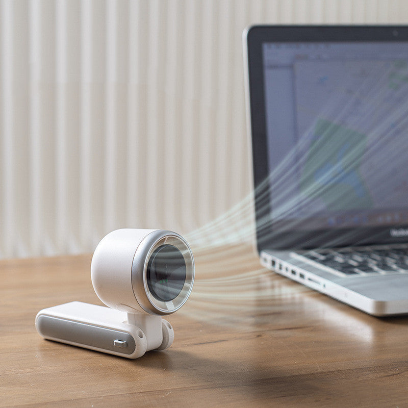Shopi Vella portable mini fan rechargeable in white on desk next to laptop blowing cool air