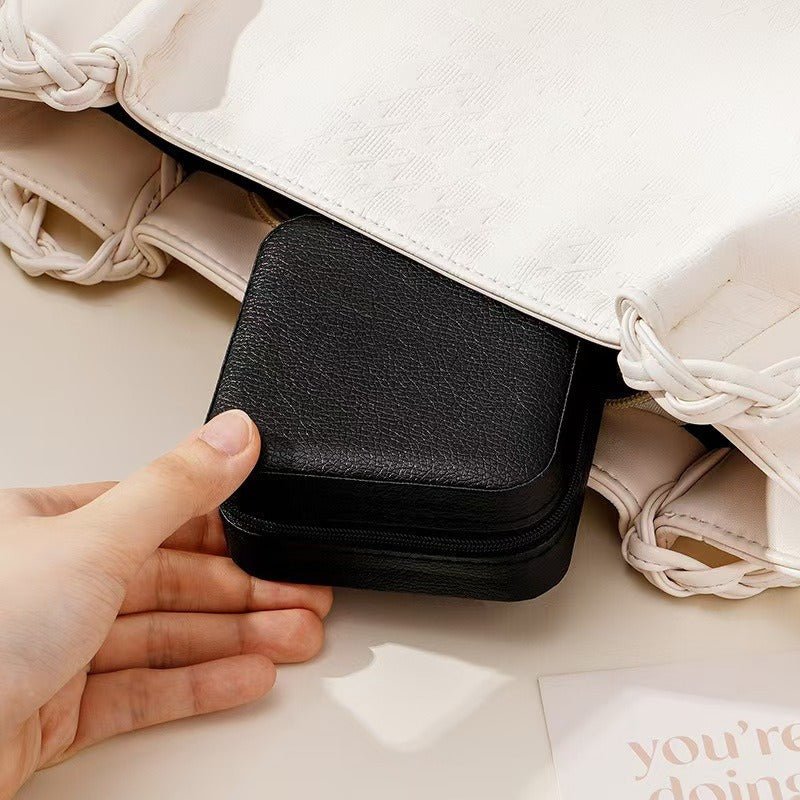 Shopi Vella portable travel jewelry box in black being placed inside a white handbag