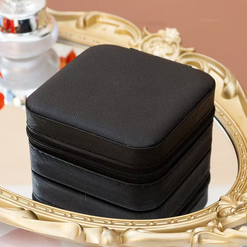 Shopi Vella black portable travel jewelry box with zipper closure placed on decorative mirror tray
