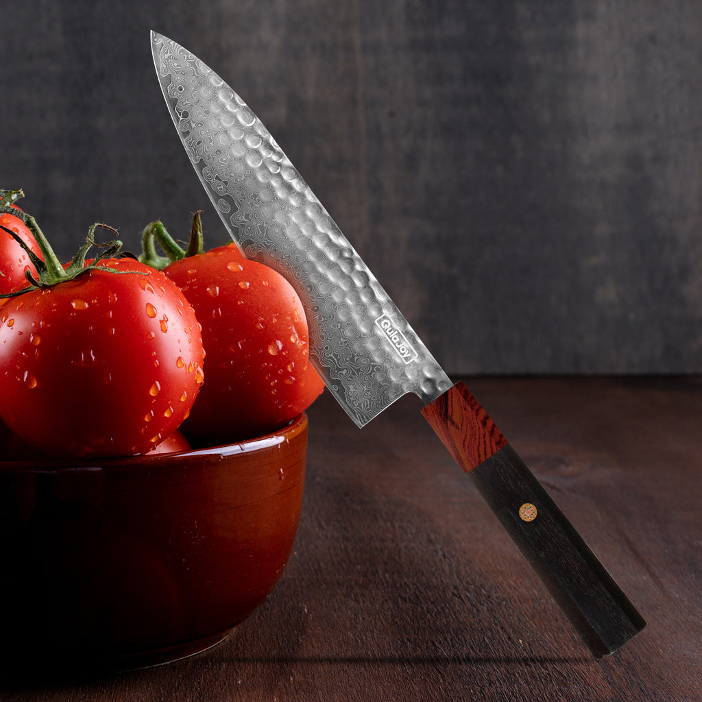 Damascus knife with African rosewood handle next to fresh tomatoes in a bowl on wooden surface
