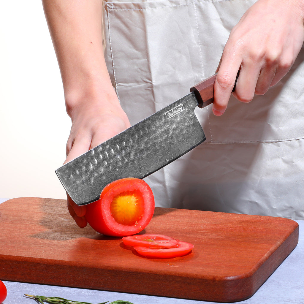 Damascus knife with African rosewood handle slicing a red bell pepper on wooden cutting board