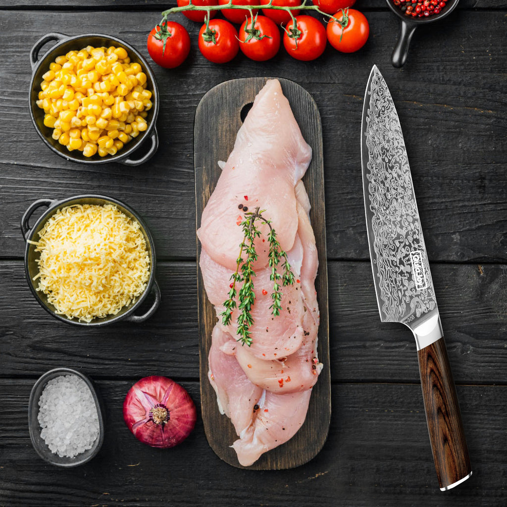 German steel kitchen knife with detailed patterned blade and wooden handle next to raw chicken and vegetables