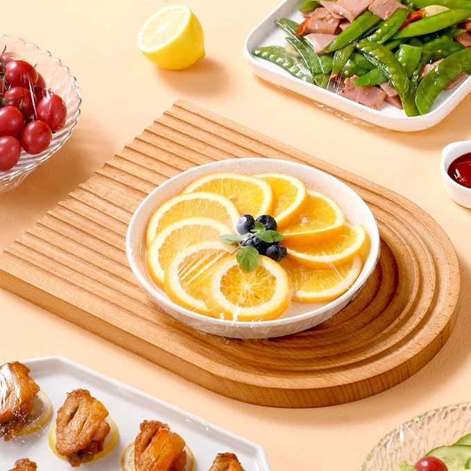 Reusable plastic bowl covers on fruit bowl with orange slices on wooden board by Shopi Vella