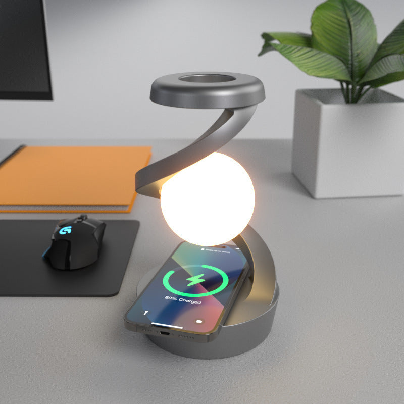Rotating moon desk lamp with wireless charging on a desk next to a smartphone charging and office accessories
