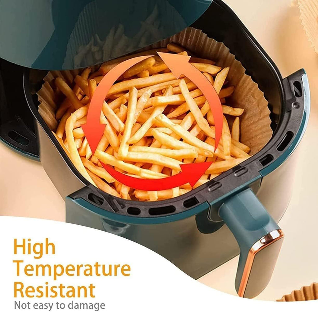 Round oil absorbing baking paper inside air fryer basket holding crispy golden french fries