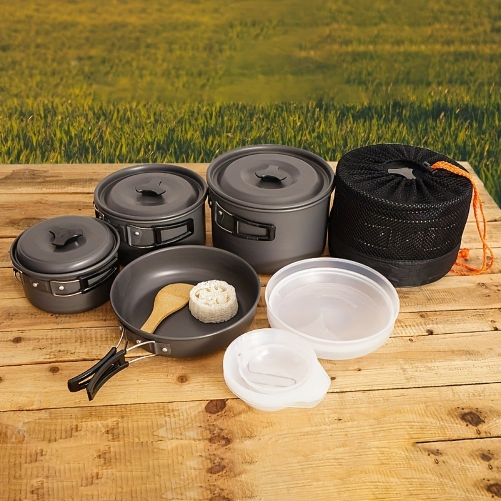 Shopi Vella RV camping pot set with multiple pots, a frying pan, and storage bag on wooden surface