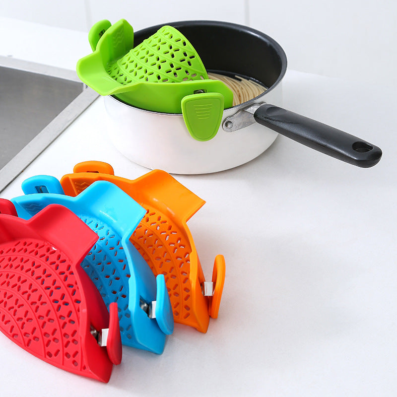 Shopi Vella silicone pot side drain stopper in green attached to pot with pasta and additional red blue orange stoppers