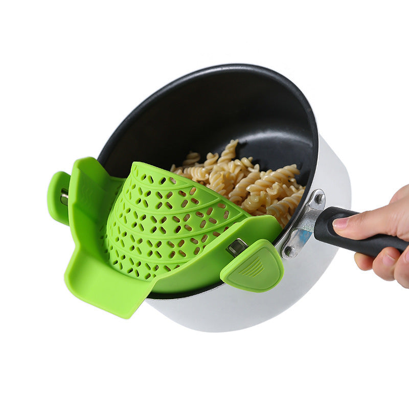 Green silicone pot side drain stopper on black saucepan draining cooked pasta