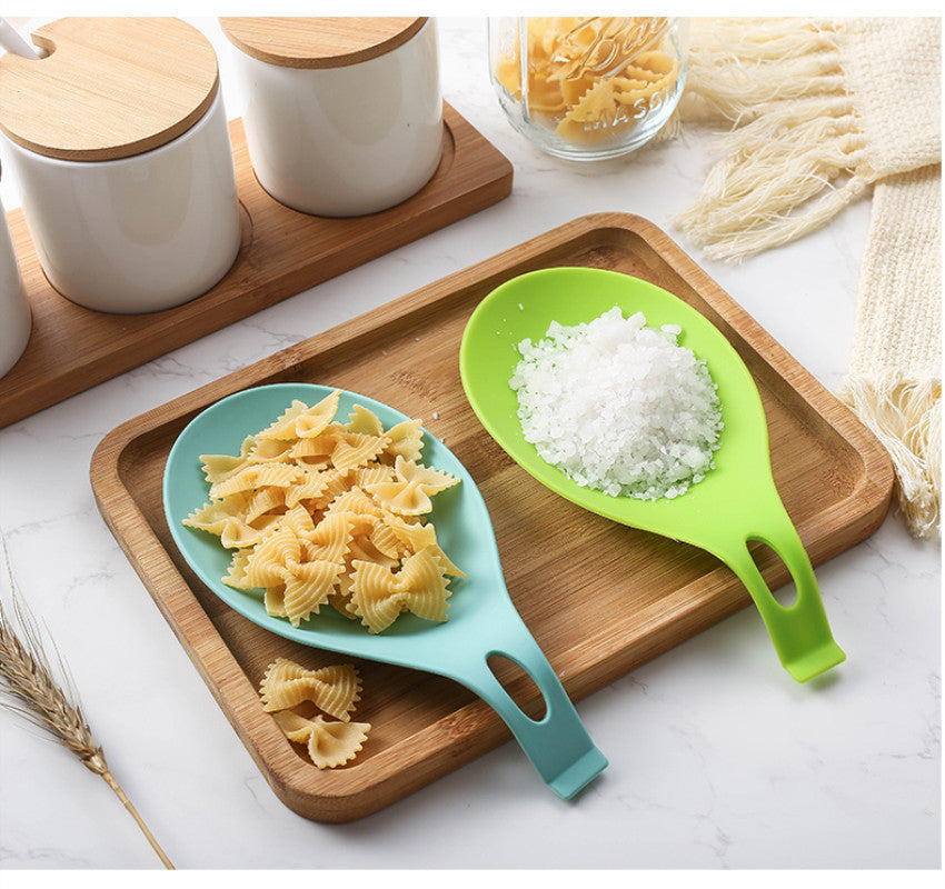 Blue and green silicone spoon rest for kitchen holding pasta and salt on wooden tray