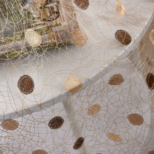 Close-up of sheer fabric with brown and beige polka dots and swirling lines on simple blackout curtains