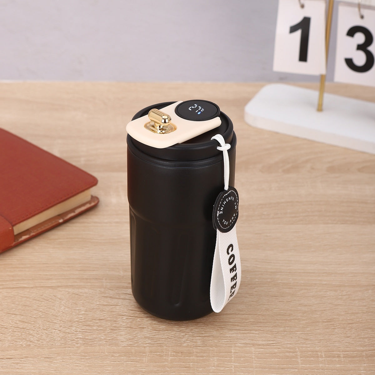 Shopi Vella black smart thermal coffee mug with temperature display and white strap on wooden table