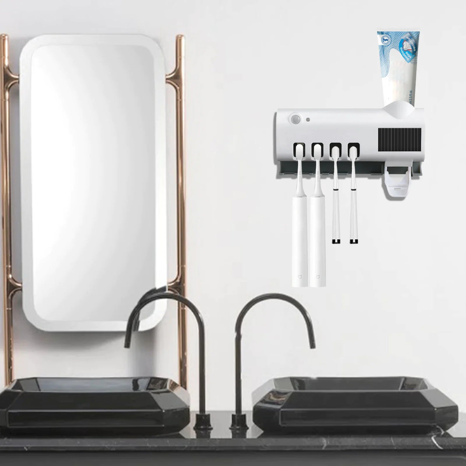 Smart UV toothbrush sterilizer mounted on bathroom wall holding toothbrushes and toothpaste above black sinks