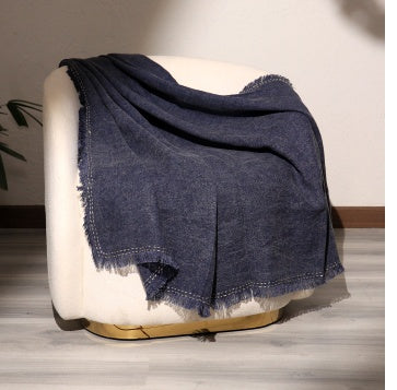 Shopi Vella cushion cover featuring a soft living room blanket for adults in dark blue draped over a white chair