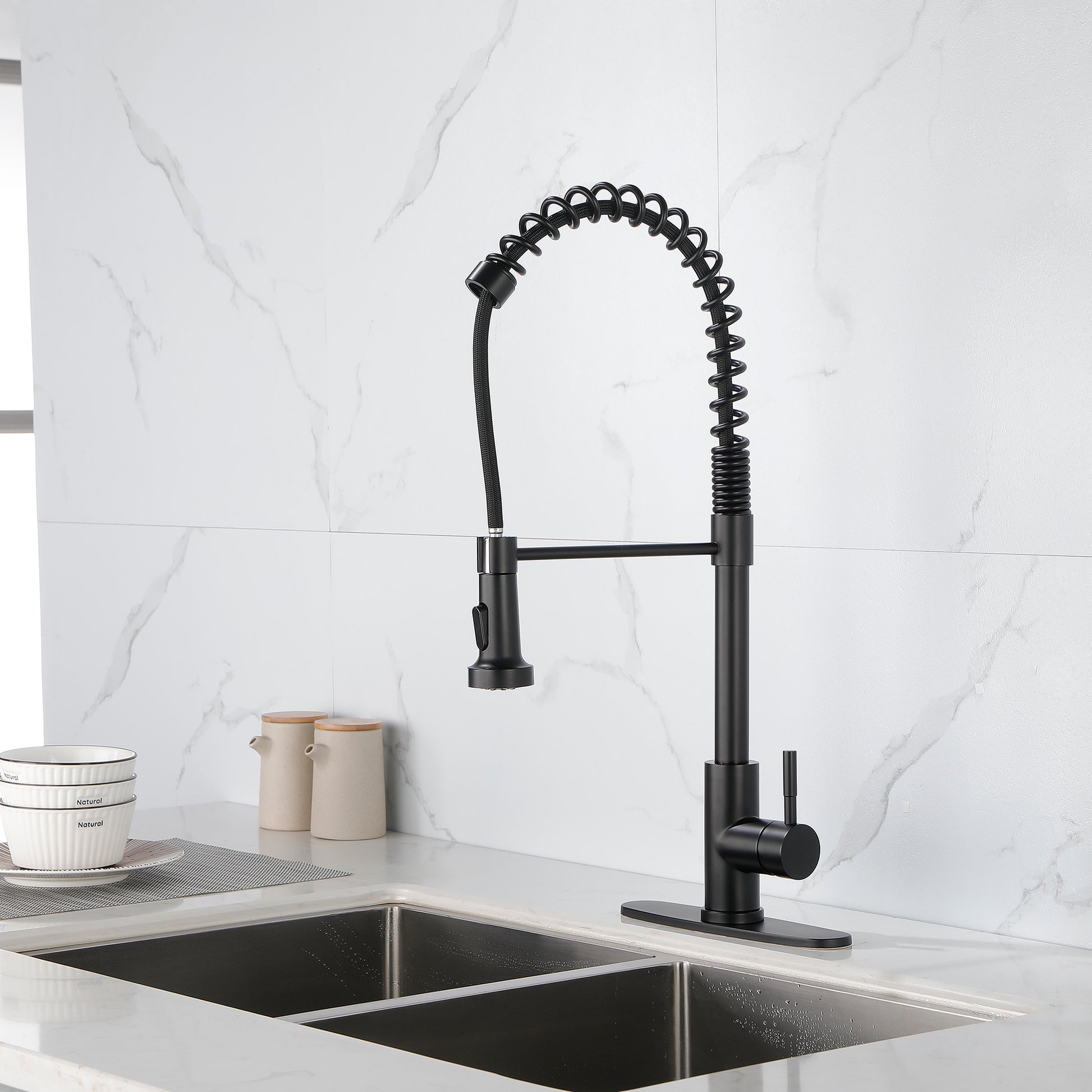 Modern black solid brass kitchen faucet with flexible spring spout installed on a stainless steel sink