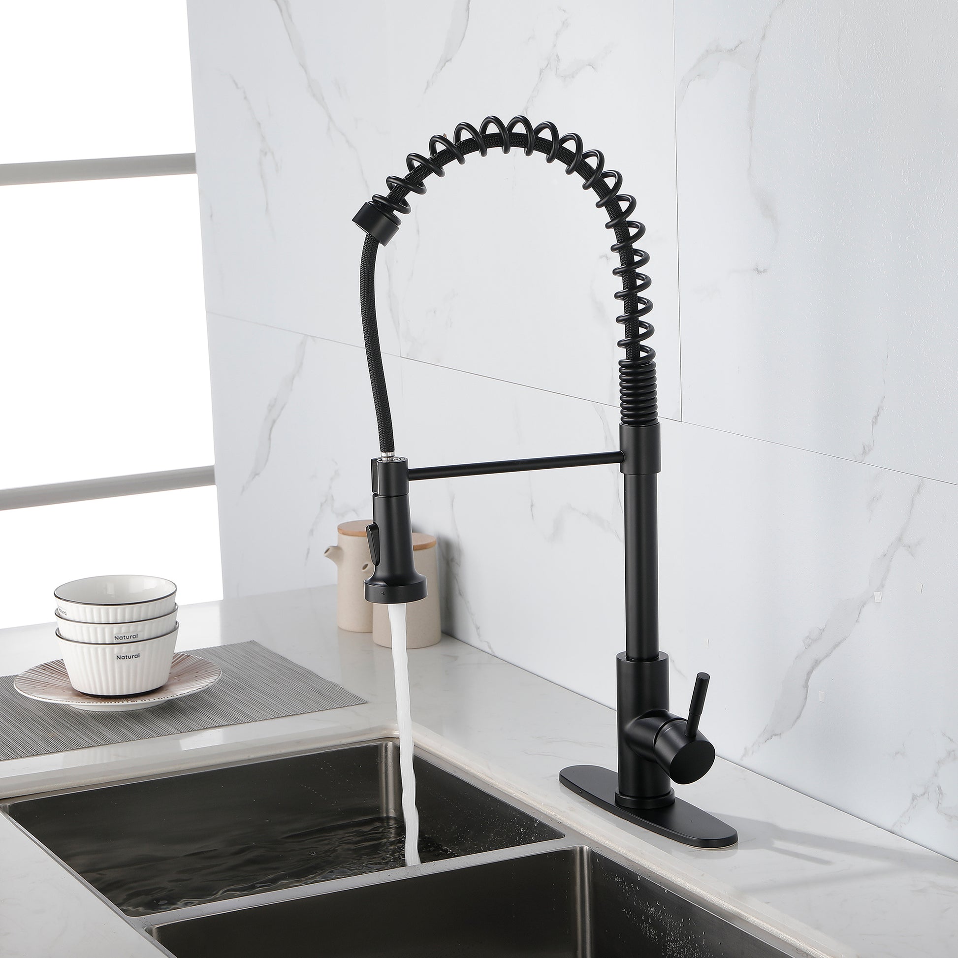 Matte black solid brass kitchen faucet with spring coil design installed on stainless steel sink