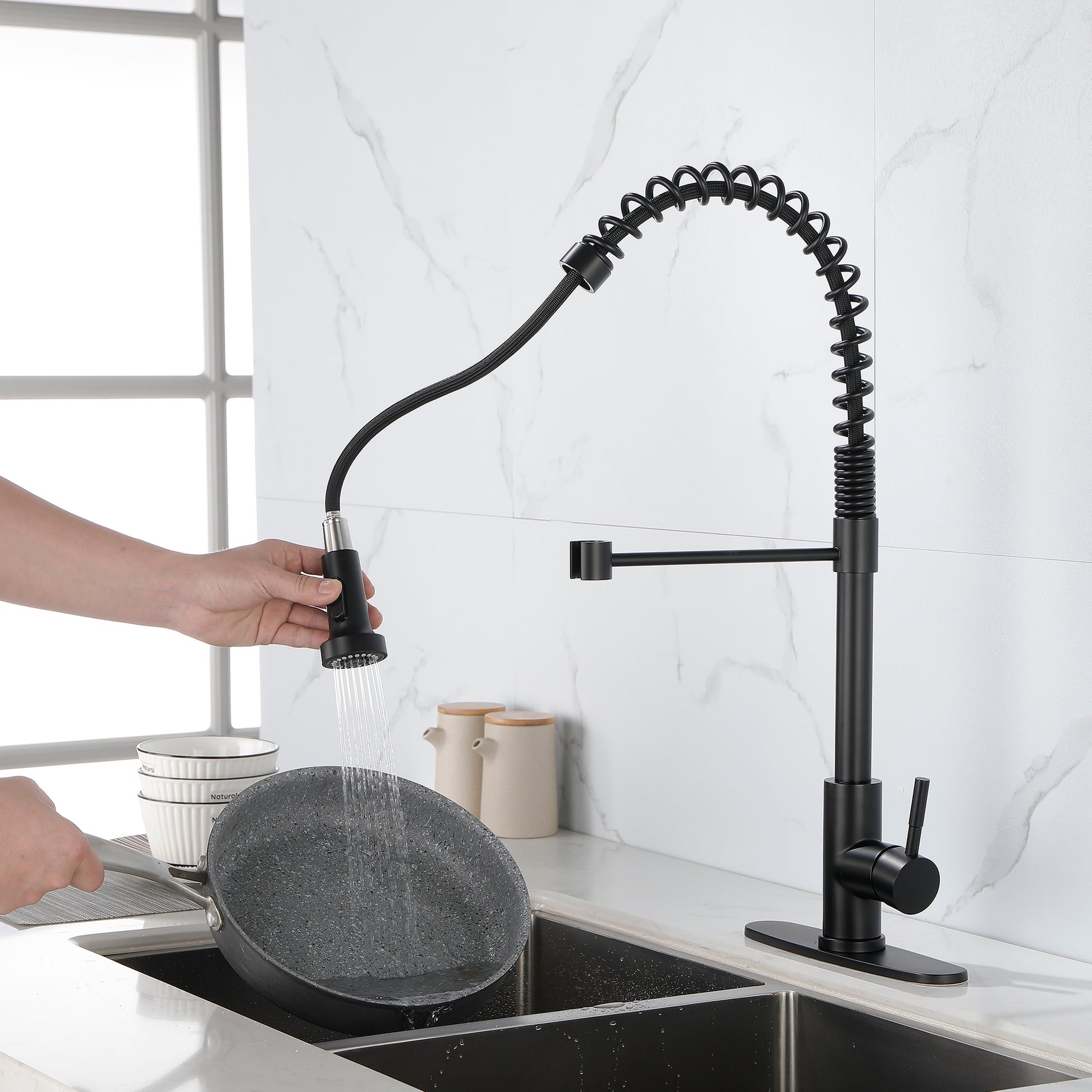 Matte black solid brass kitchen faucet with flexible spring spout and single handle in modern kitchen