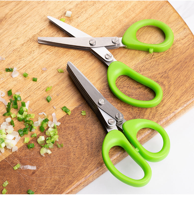 Shopi Vella stainless steel herb scissors with green handles cutting fresh herbs on wooden board