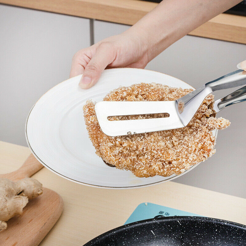 Shopi Vella stainless steel kitchen tongs holding breaded fried cutlet over white plate