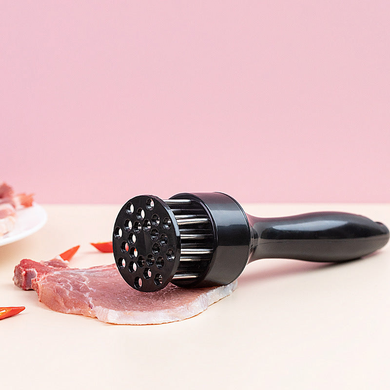 Shopi Vella stainless steel meat tenderizer with black handle resting on raw meat slice