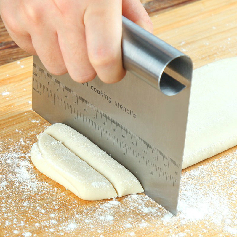Shopi Vella pizza dough cutter tool slicing dough on a floured wooden surface