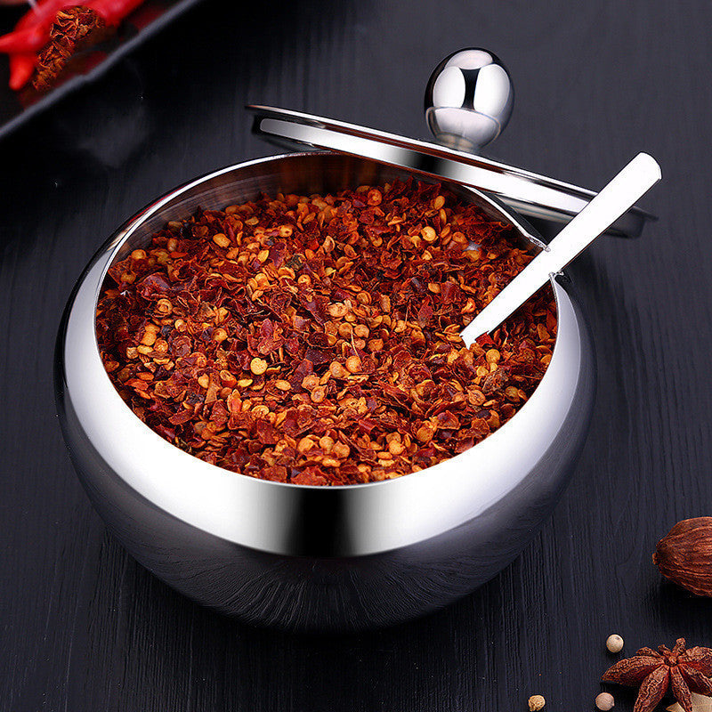Shopi Vella stainless steel seasoning pot filled with crushed red chili flakes and a small spoon