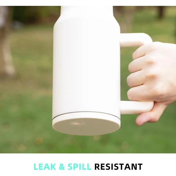 White stainless steel travel mug with handle held outdoors highlighting leak and spill resistant design
