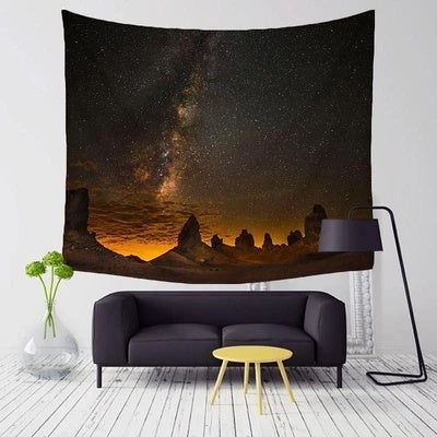 Starry night wall tapestry depicting a night sky with stars and rocky landscape above a modern black sofa