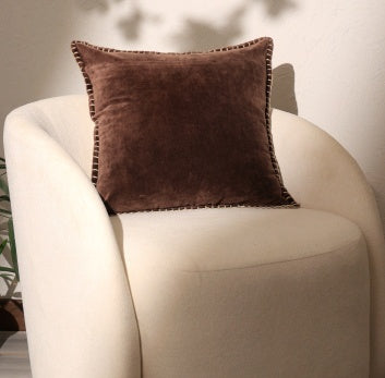 Shopi Vella stonewashed cotton velvet throw pillow case in brown on a cream armchair