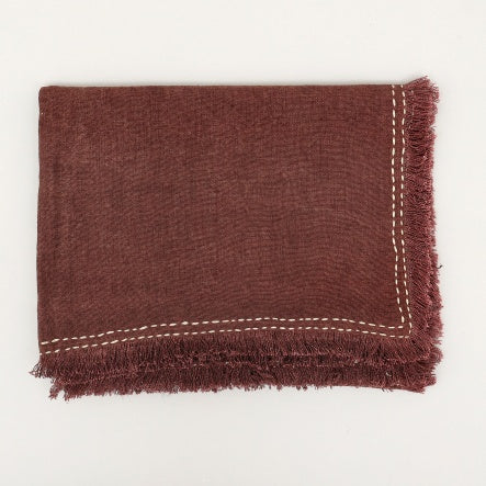Shopi Vella cushion cover in deep brown with fringe edges and stonewashed linen throw blanket texture