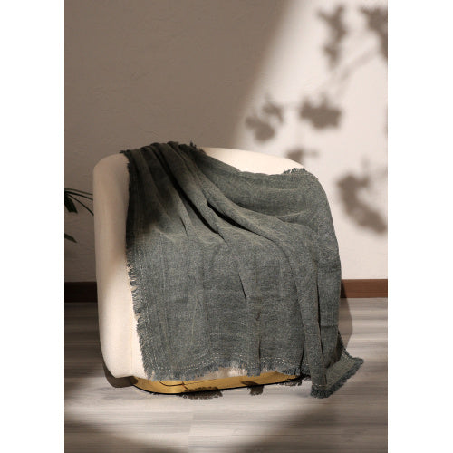 Stonewashed linen throw blanket draped over a white cushioned chair in soft natural light