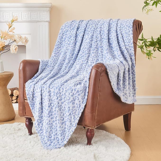 Shopi Vella super soft women's blanket in blue leopard print draped over brown leather armchair