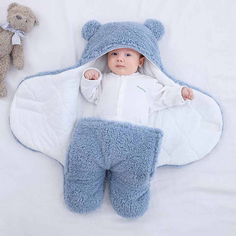 Baby lying on a thick winter baby quilt from Shopi Vella with blue fuzzy hood and leg covers
