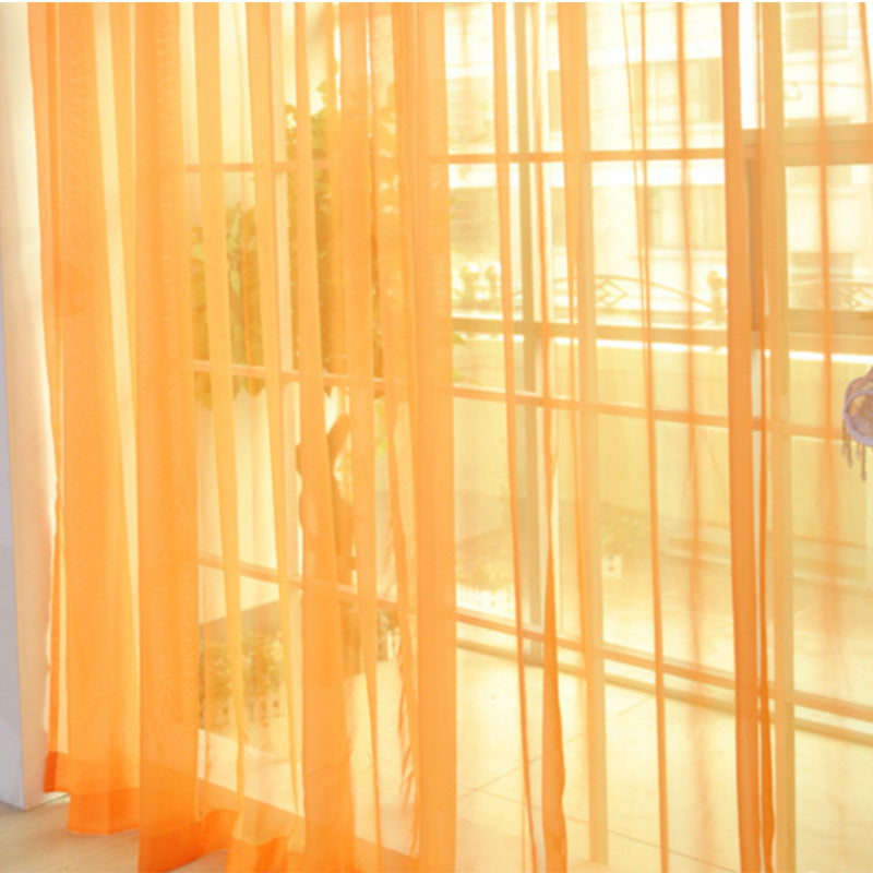Orange transparent tulle window curtains hanging in front of large glass doors letting in sunlight