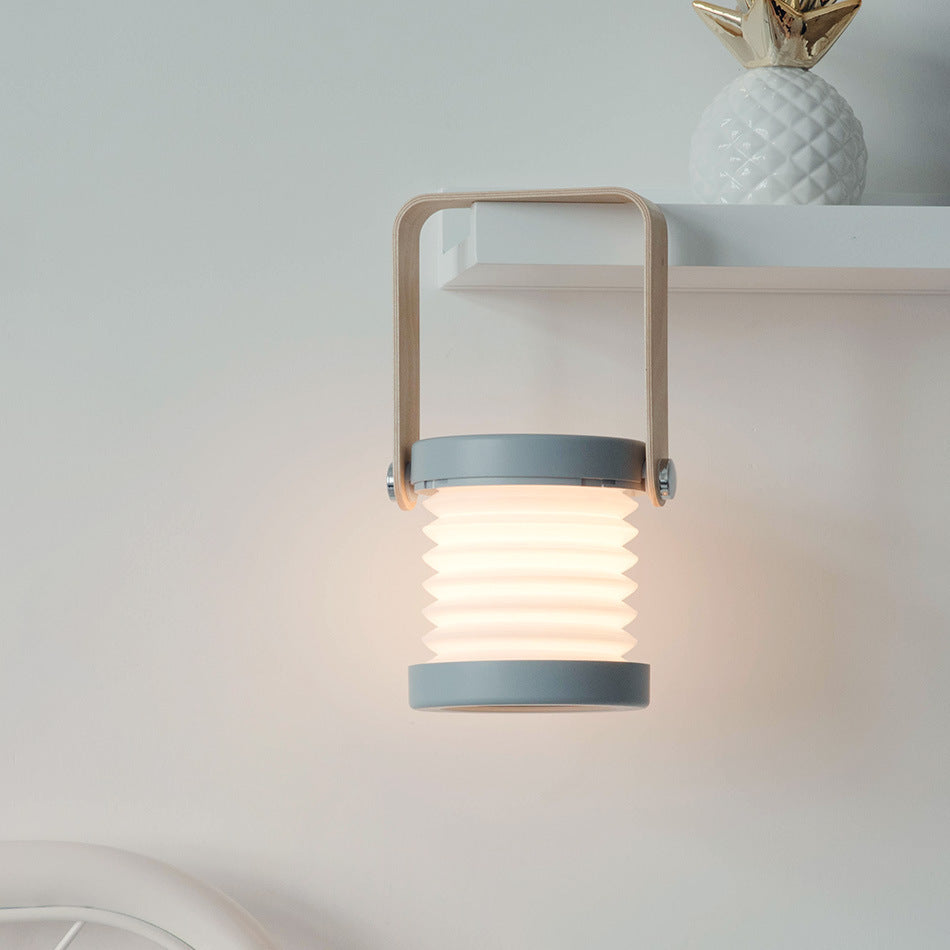 Modern USB rechargeable lantern for home decor hanging on a white wall under a shelf with a decorative pineapple