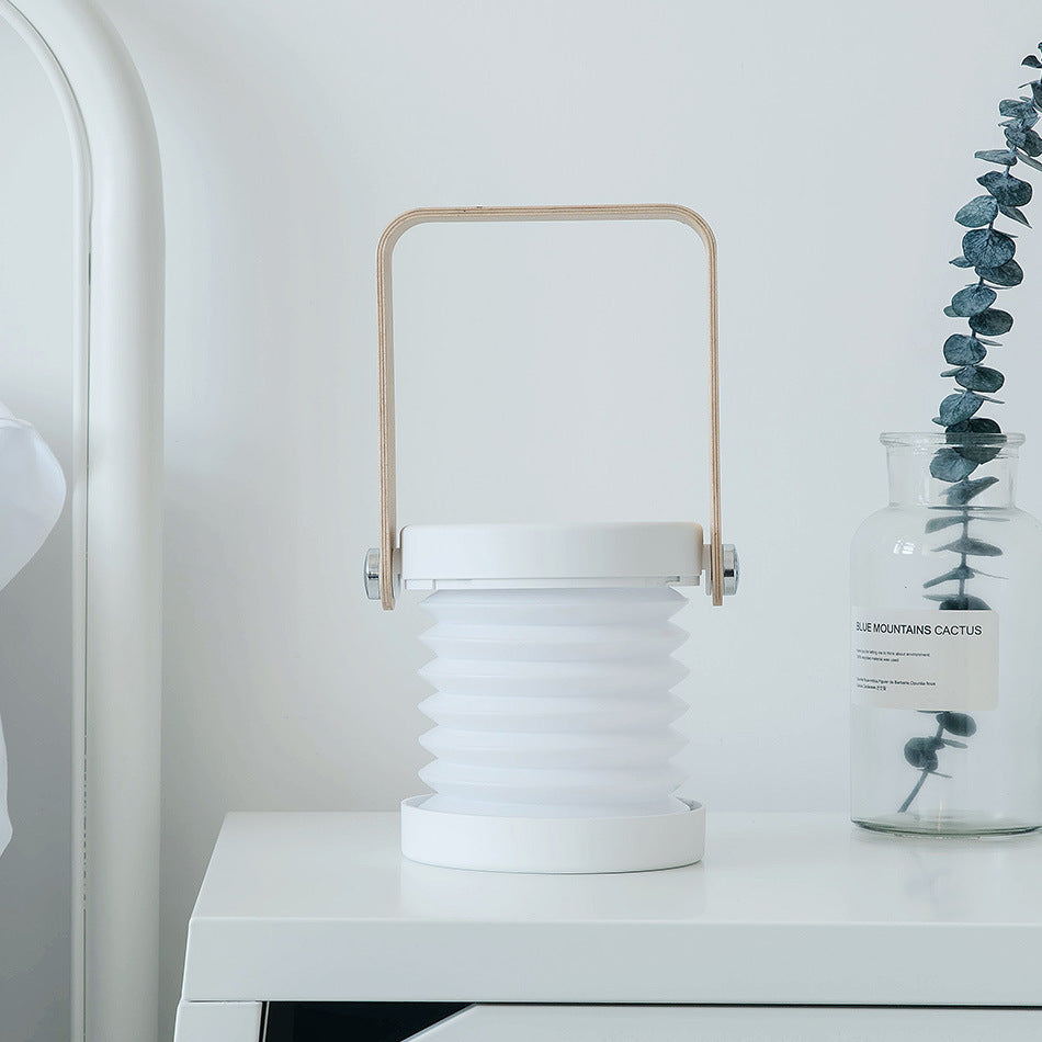 USB rechargeable lantern for home decor with white accordion design and wooden handle on white table