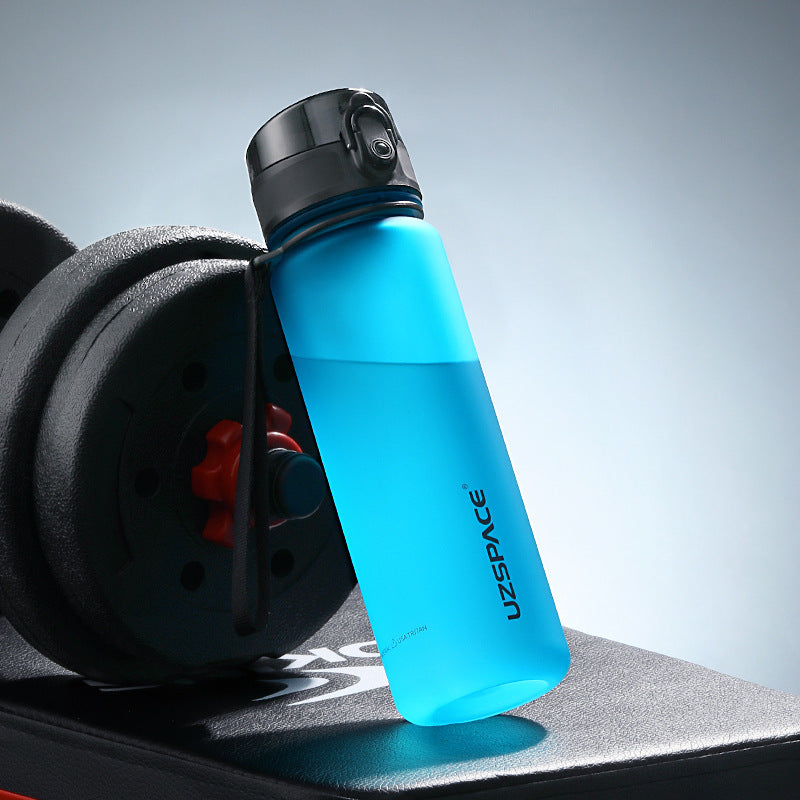 Shopi Vella colorful sports water bottle in blue with black cap next to gym weights