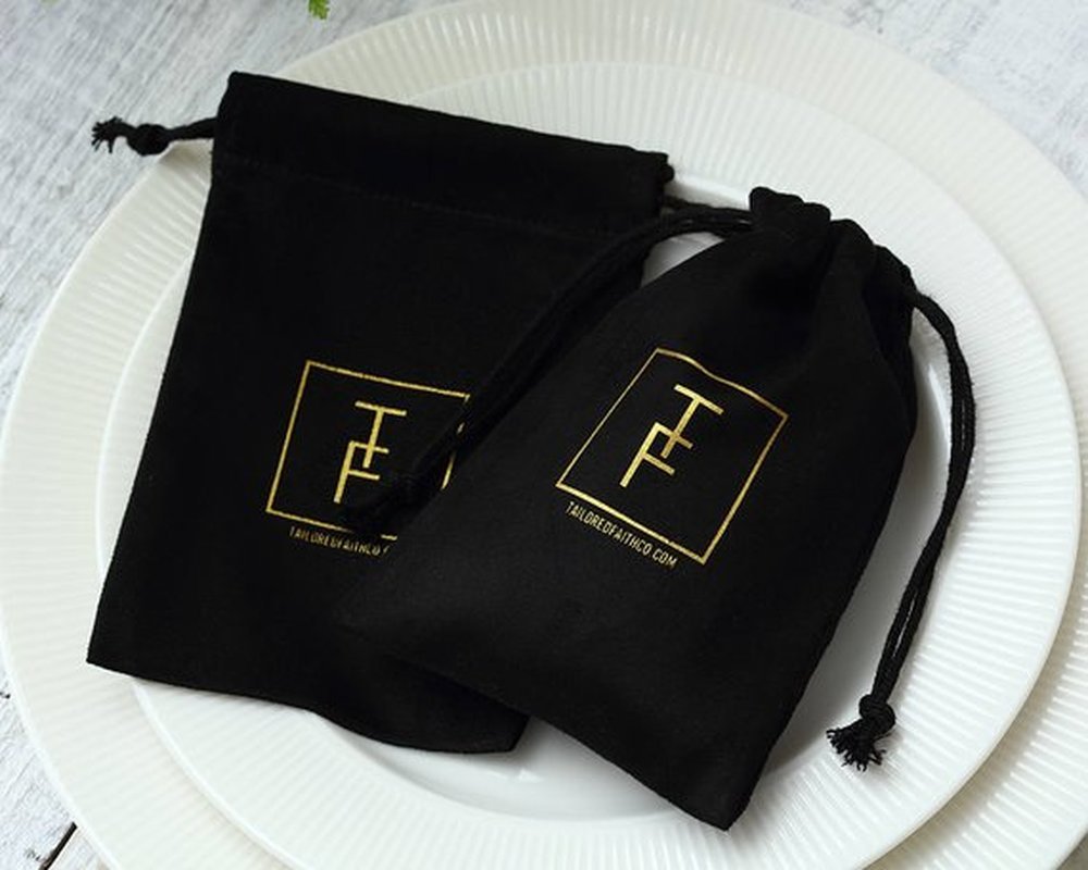 Shopi Vella black velvet jewelry gift bag with gold logo on white plate for home storage