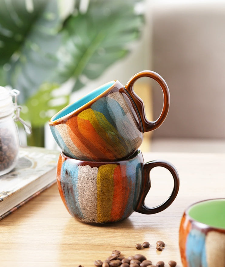 Shopi Vella creative ceramic coffee mug with colorful striped design stacked on wooden table