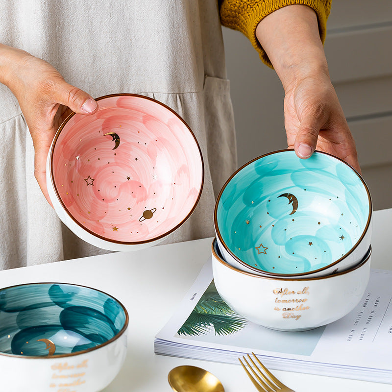 Hand holding cute ceramic breakfast bowl in pink and blue with celestial designs from Shopi Vella kitchen storage