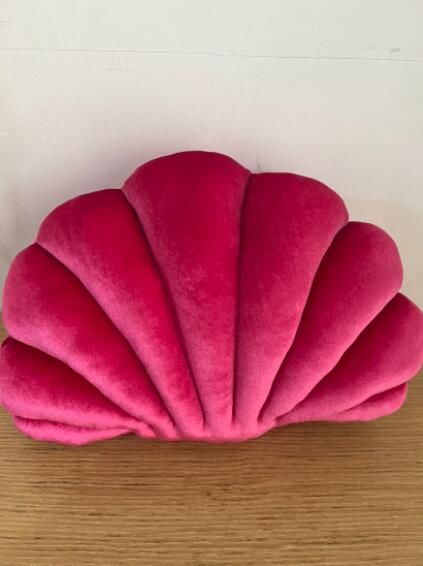 Shopi Vella cute shell nap pillow for kids in bright pink plush fabric on wooden surface