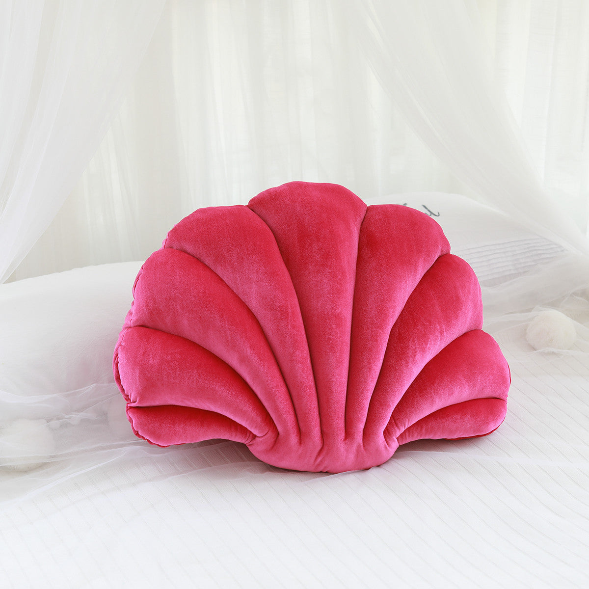 Shopi Vella cute shell nap pillow for kids in bright pink velvet on white bedding