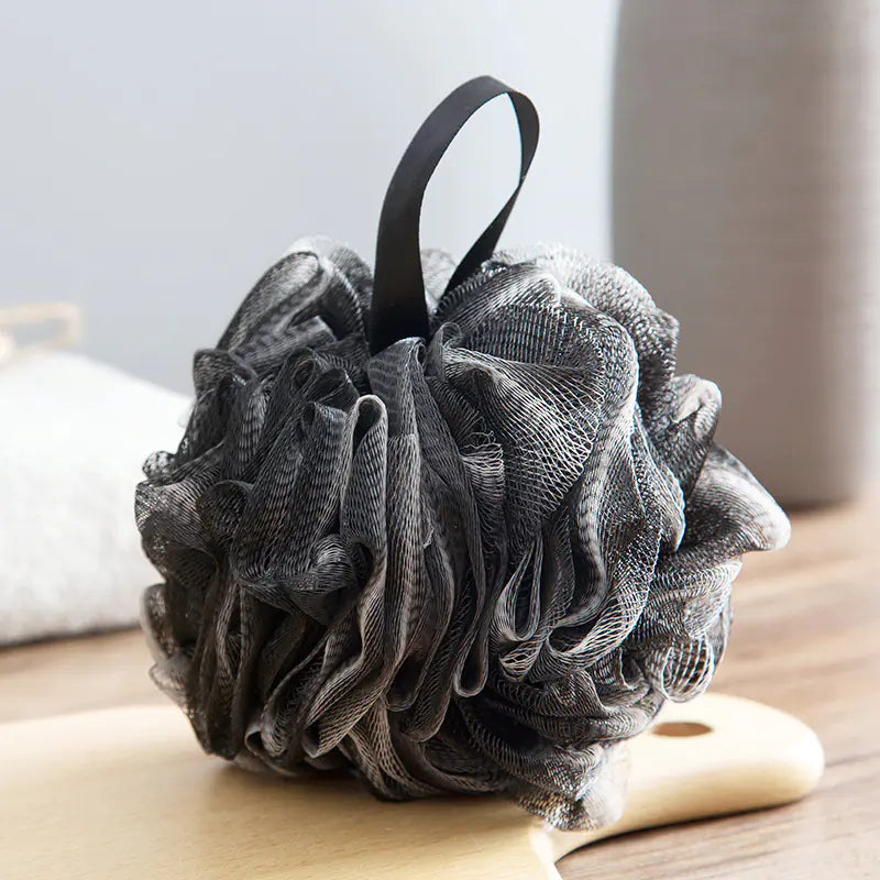 Black extra large bath sponge for men with hanging loop on wooden board in bathroom
