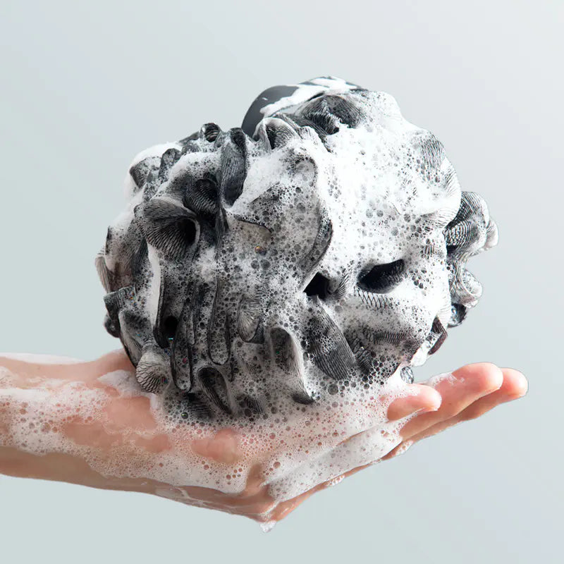 Extra large bath sponge for men covered in foam held in hand for deep cleansing and exfoliating