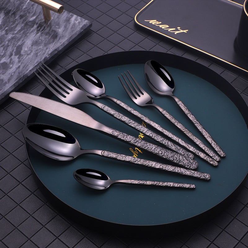 Elegant gold cutlery set for dinner parties with textured handles on black plate